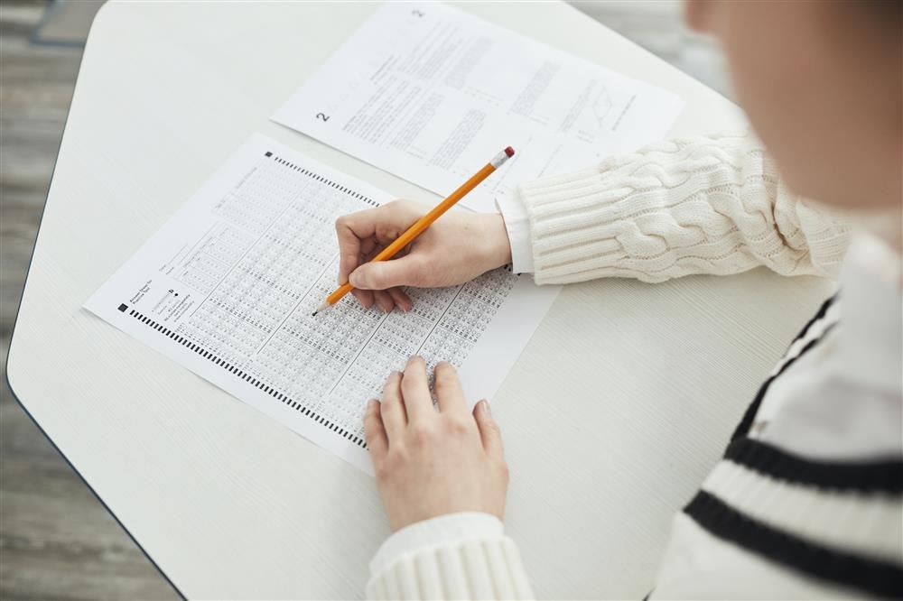 person taking test on scantron, sitting at desk or table.
