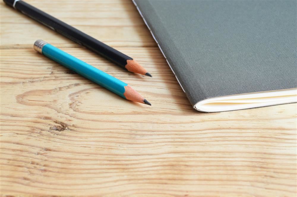  notebook and two pencils on desk